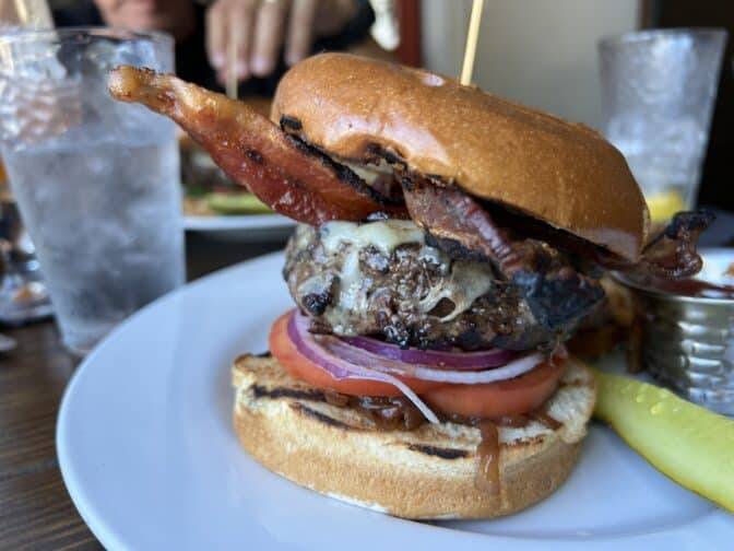 the delicious burger at Riverpark Terrace topped with onion, cheese, bacon and a browned bun