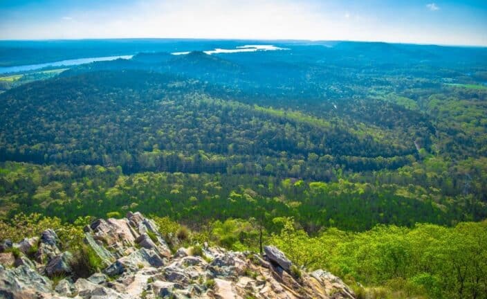 an aerial view of the Western Arkansas' Mountain Frontier with blue skies and green foliage, an example of what to see during your romantic getaway