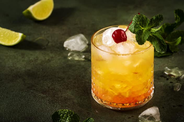Easy Mai Tai cocktail with rum, liqueur, syrup, lime juice, mint and crushed ice. Dark background