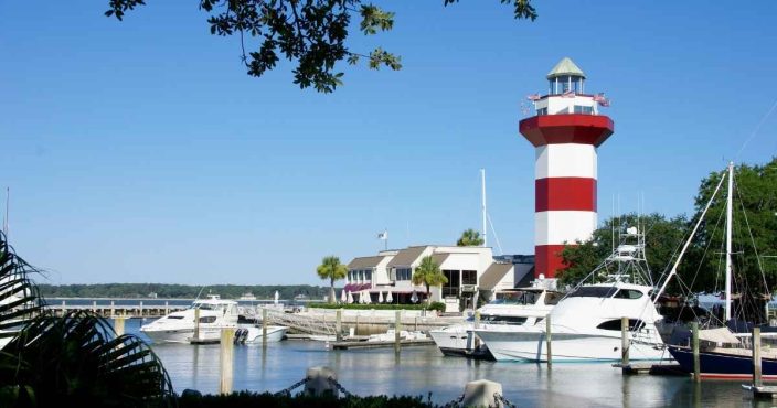 Hilton head lighthouse with boats in the harbor on a blue sky day 