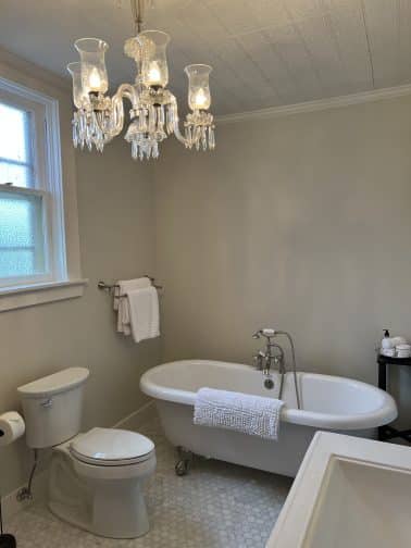 the ensuite with bath tub, chandelier, and toilet in Bryan Texas
