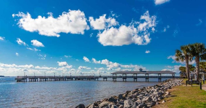 a large pier on St. Simons island with bright blue sky, rocks, and water, an example of romantic getaways in Georgia