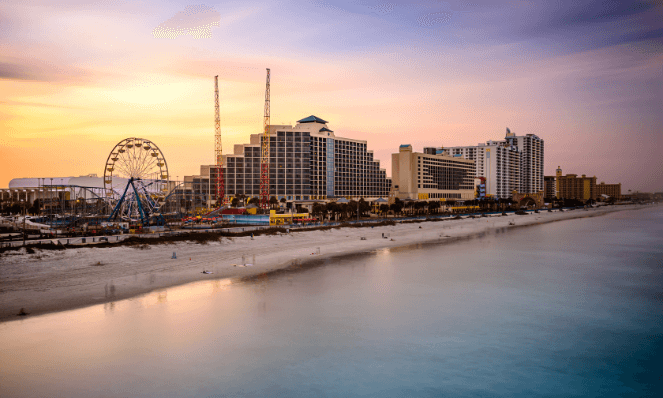 The coastline of Daytona Beach, Florida with sunset skies, high rises, and blue water. 