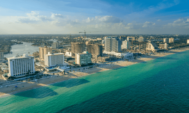 An aerial view of Fort Lauderdale with turquoise water, blue skies, high rises and beachfront. 