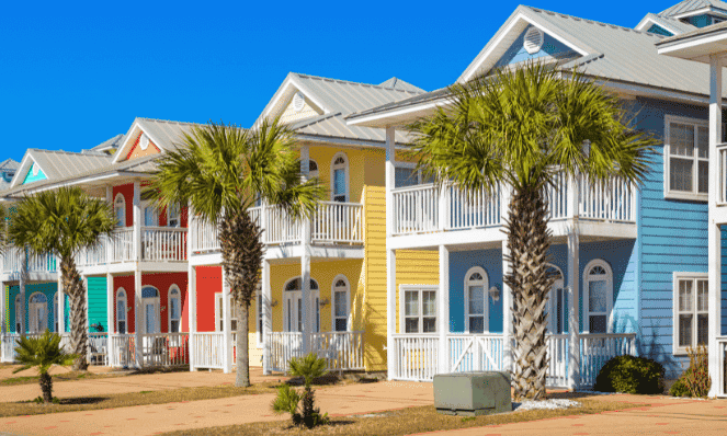 colorful houses in Panama City Beach, Florida with palm trees outside of them and blue skies