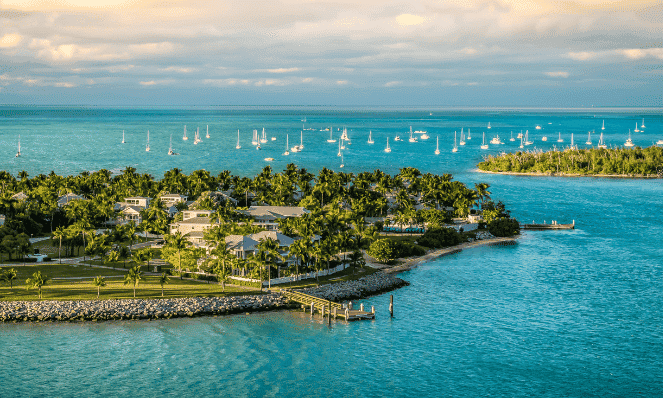 an aerial view of the Florida Keys with turquoise waters, green palm trees, and many sail boats