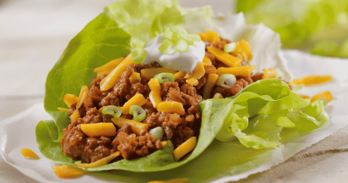 ground beef tacos in a lettuce wrap instead of a taco shell with cheese, sour cream, and green onions