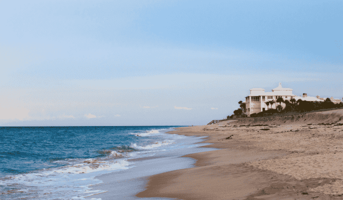 a beach at Vero Beach Florida with a large yellow house in the distance, blue waters, and blue skies