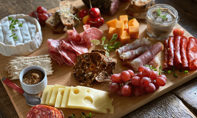 a charcuterie board with an assortment of cured meats, cheeses, fruits, spreads, and crackers for the making of a cheese board