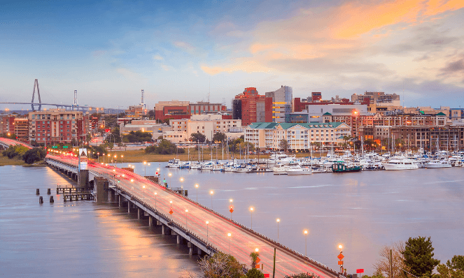 an aerial view of charleston, sc with waterfront homes, boats, a long bridge and sunset skies, the perfect place for a romantic getaway on the beach