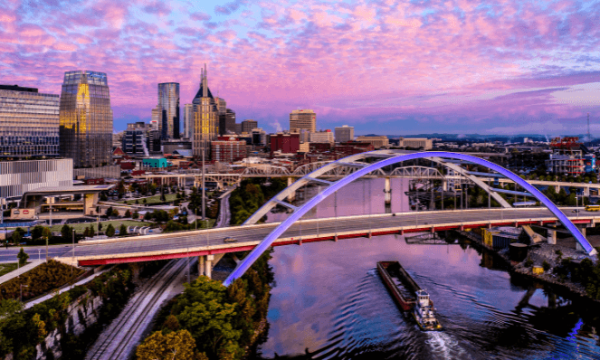 aerial view of a city in Tennessee with pink and purple skies a bridge and high rise buildings representing Tennessee romantic getaways