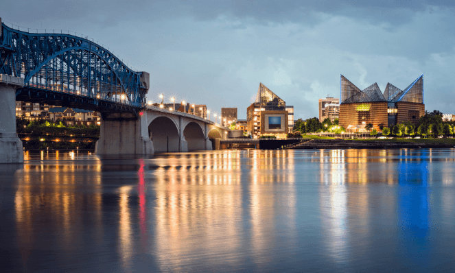 Chattanooga Tennesee river with grey skies and a large bridge with buildings on the banks