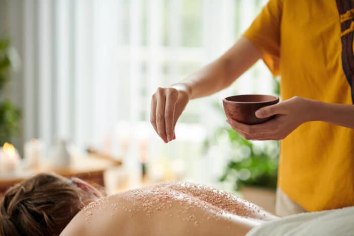 a person pouring salt on a woman's back