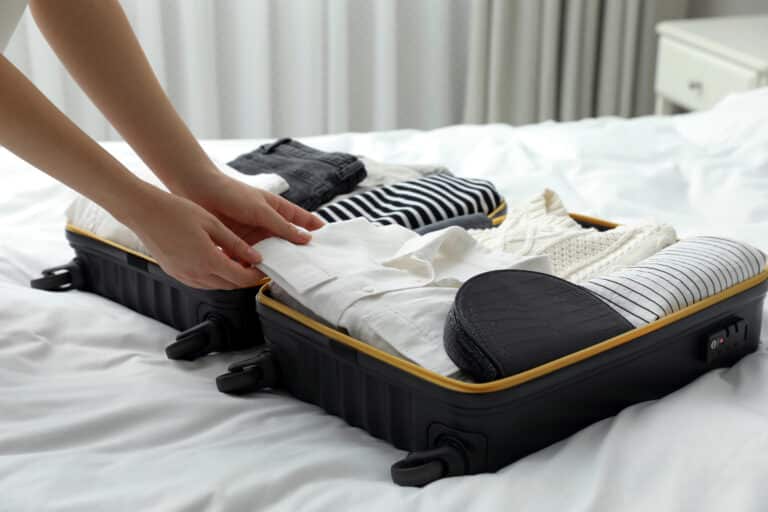 a person packing clothes in a suitcase