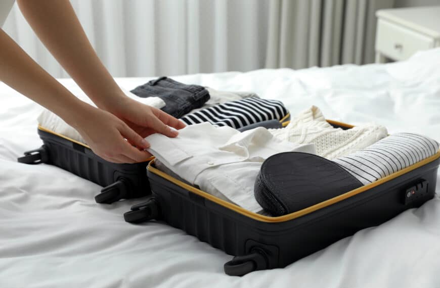 a person packing clothes in a suitcase