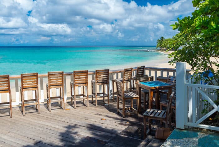 a table and chairs on a deck overlooking a beach