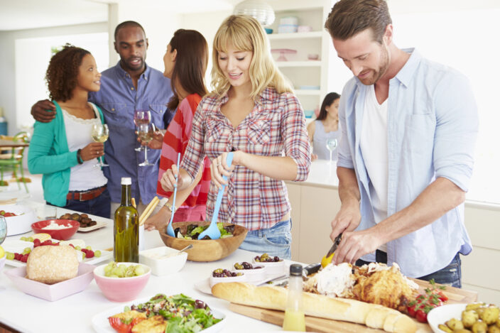 a group of people standing around a table with food